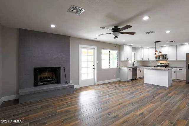 an open kitchen with a fireplace and wooden floor