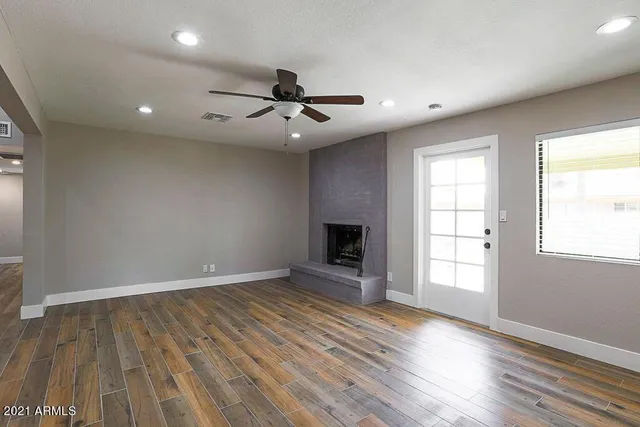 an empty room with wooden floor fireplace and windows
