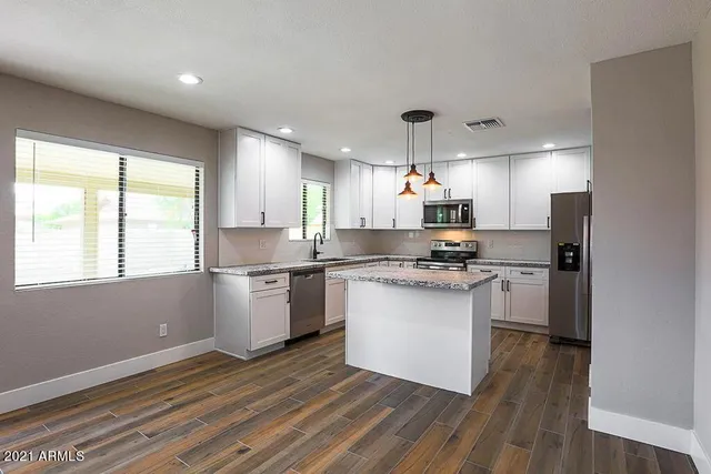 a kitchen with a refrigerator wooden floor white cabinets and a window