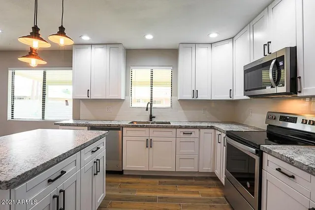 a kitchen with stainless steel appliances granite countertop a sink a stove and a microwave