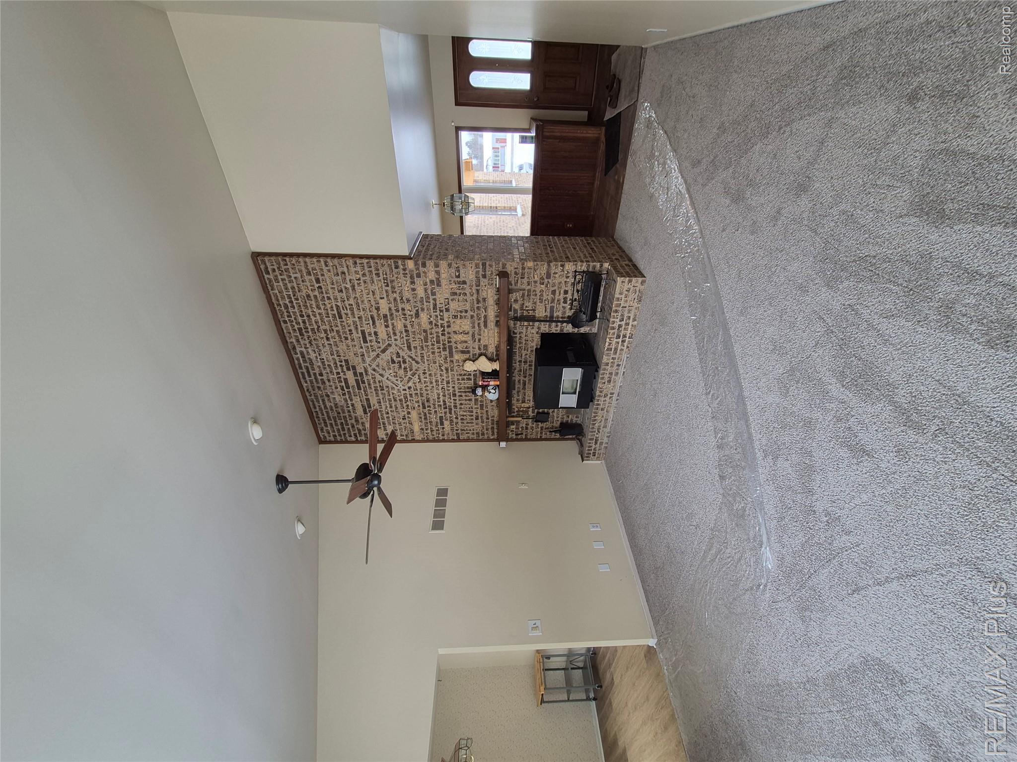 1115 Turrill Road Lapeer, MI 48446 - Photo 2 of 50 Unfurnished living room featuring a fireplace, lofted ceiling, carpet flooring, and a ceiling fan