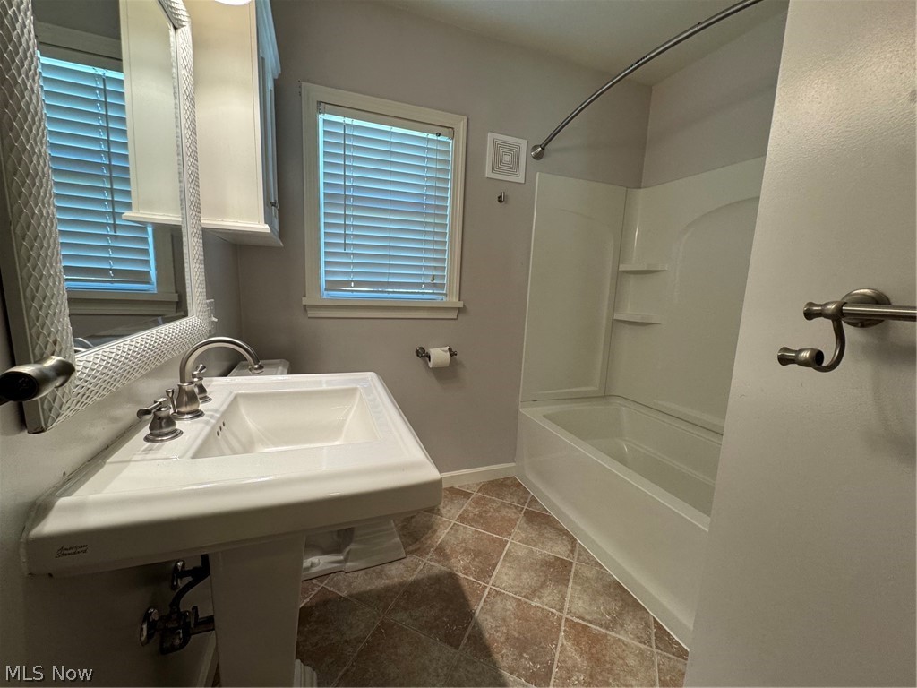 145 Anna Avenue Northwest Canton, OH 44708 - Photo 14 of 27 Bathroom featuring a pedestal sink, brushed nickel fixtures, a built-in medicine cabinet, a window with blinds, and a bathtub with an integrated shower surround