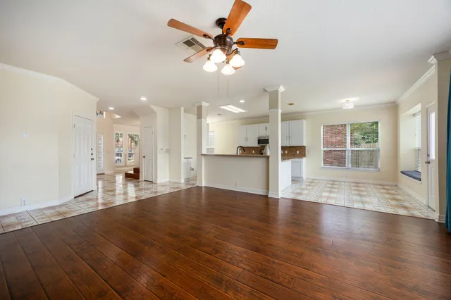 an empty room with wooden floor and a kitchen view