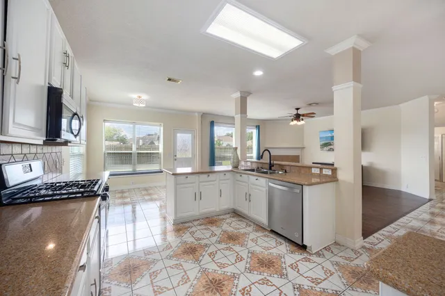 a kitchen with stainless steel appliances granite countertop a stove a sink and a microwave