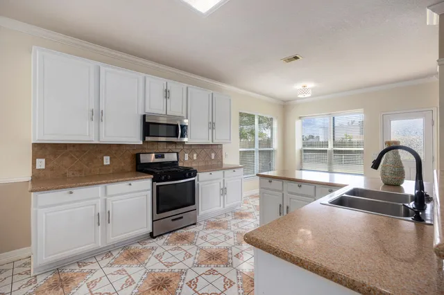 a kitchen with granite countertop a stove sink and cabinets
