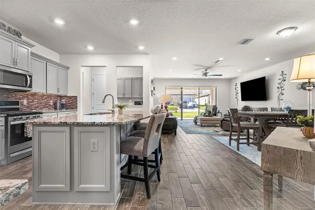 a kitchen with stainless steel appliances kitchen island granite countertop a stove top oven a sink a dining table and chairs