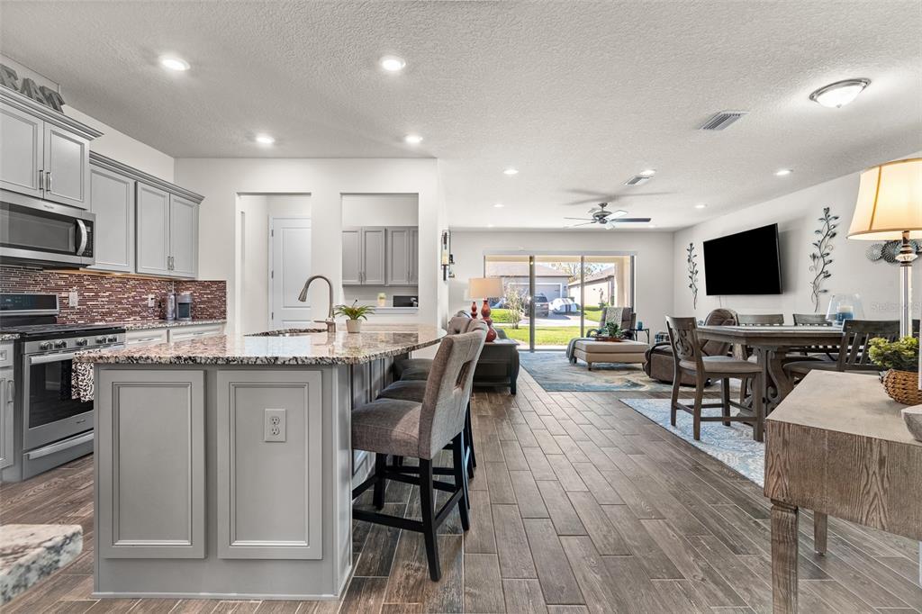 2825 Murray Pass Odessa, FL 33556 - Photo 11 of 43 a kitchen with stainless steel appliances kitchen island granite countertop a stove top oven a sink a dining table and chairs