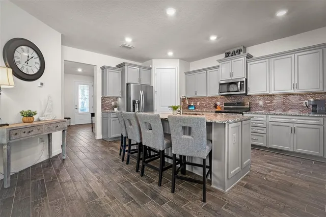 a kitchen with kitchen island granite countertop a sink a stove a refrigerator cabinets and a dining table