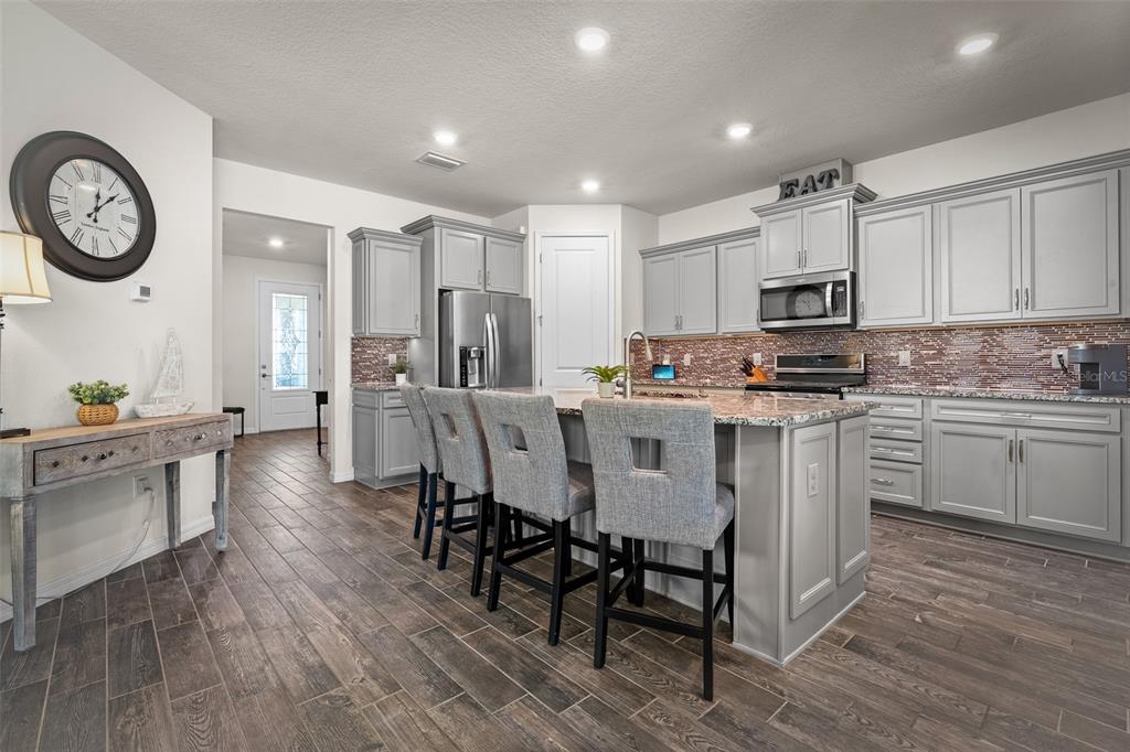 2825 Murray Pass Odessa, FL 33556 - Photo 6 of 43 a kitchen with kitchen island granite countertop a sink a stove a refrigerator cabinets and a dining table