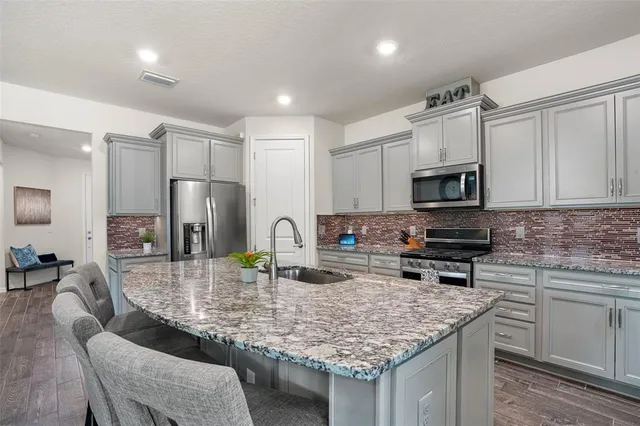 a kitchen with kitchen island granite countertop a sink counter top space appliances and cabinets