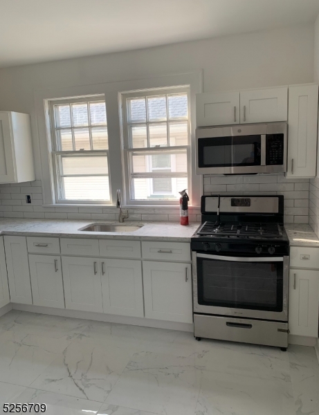 a kitchen with stainless steel appliances granite countertop white cabinets and a stove top oven