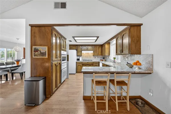 a kitchen with stainless steel appliances kitchen island granite countertop a table chairs and a refrigerator