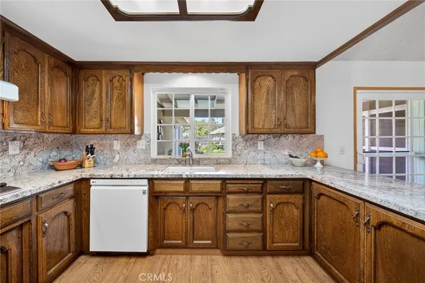 a kitchen with stainless steel appliances granite countertop wooden cabinets a sink and dishwasher with wooden floor