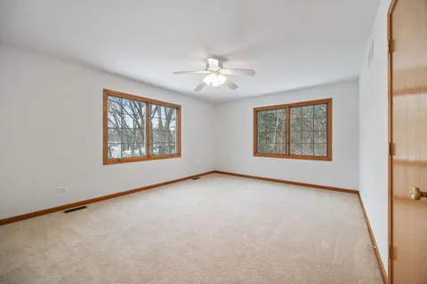 an empty room with windows and ceiling fan