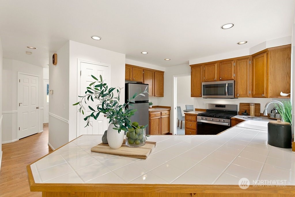 1315 231st Street Southeast Bothell, WA 98021 - Photo 11 of 34 a kitchen with stainless steel appliances granite countertop a refrigerator a stove top oven a sink with wooden floor