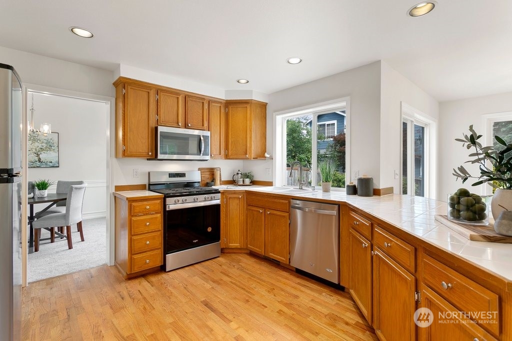1315 231st Street Southeast Bothell, WA 98021 - Photo 10 of 34 a large kitchen with stainless steel appliances granite countertop a stove a sink dishwasher and a microwave oven with wooden floor