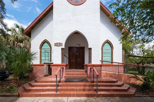 a view of a brick house with large windows and a flower plants