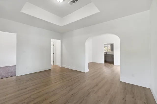 an empty room with wooden floor & windows