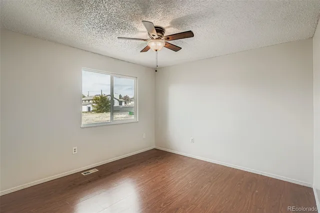 an empty room with a window and a ceiling fan