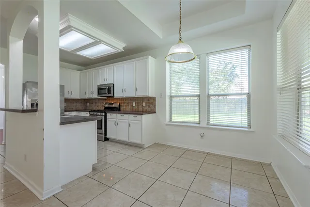a kitchen with stainless steel appliances granite countertop a stove top oven a refrigerator a sink and a window