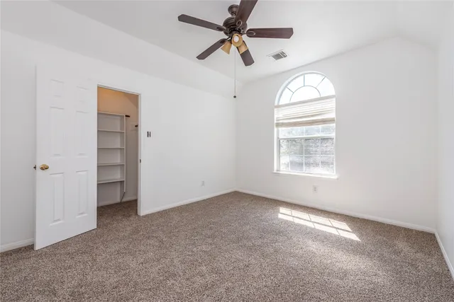 an empty room with windows and fan