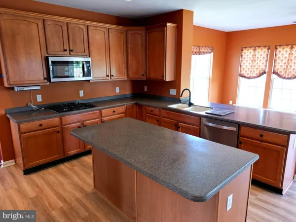 a kitchen with stainless steel appliances wooden cabinets a stove a sink and a microwave