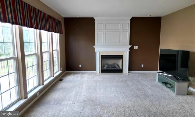 a view of an empty room with a fireplace and a window