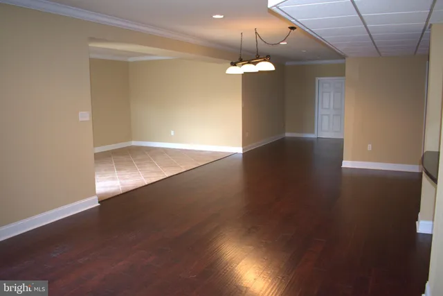 an empty room with wooden floor and chandelier fan
