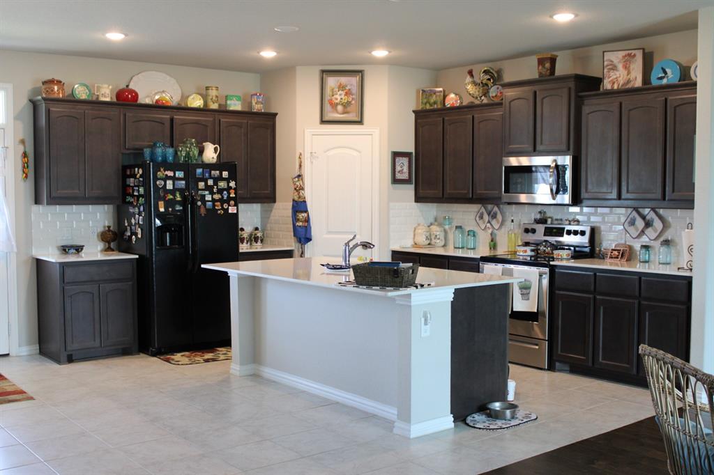 2267 County Road 4010 Decatur, TX 76234 - Photo 12 of 36 a kitchen with granite countertop a refrigerator and a stove top oven