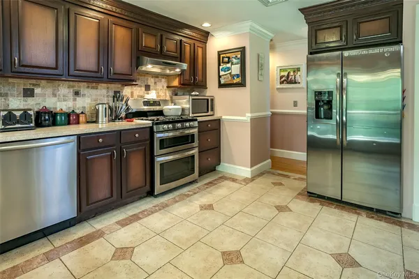 a kitchen with stainless steel appliances granite countertop a refrigerator a stove and a sink
