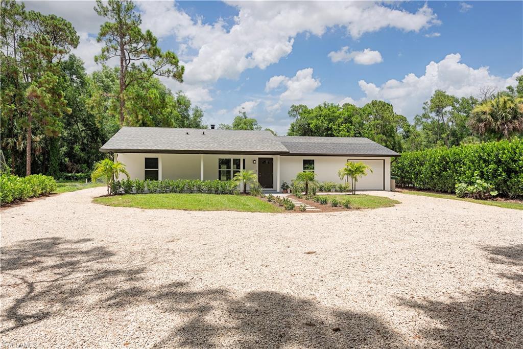 a front view of house with yard and trees around