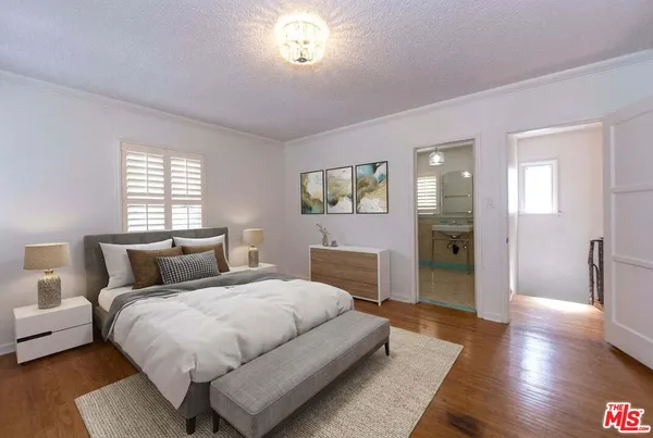 a bedroom with a large bed and wooden floor