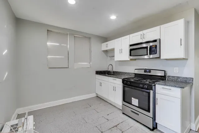 a kitchen with granite countertop white cabinets stainless steel appliances and a sink