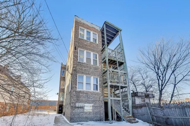 a front view of a building with large trees