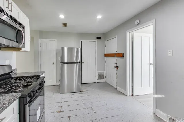 a kitchen with stainless steel appliances granite countertop a refrigerator a stove and a sink