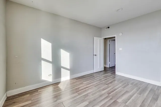 a view of an empty room with window and wooden floor
