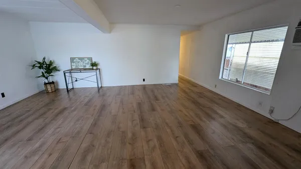 a view of a livingroom with wooden floor and a window