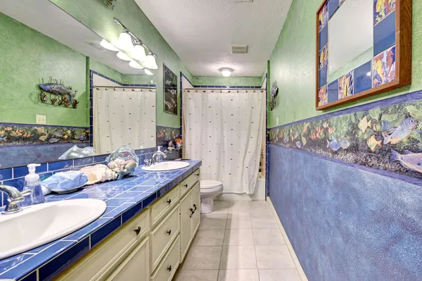a bathroom with a granite countertop double vanity sink a mirror and shower