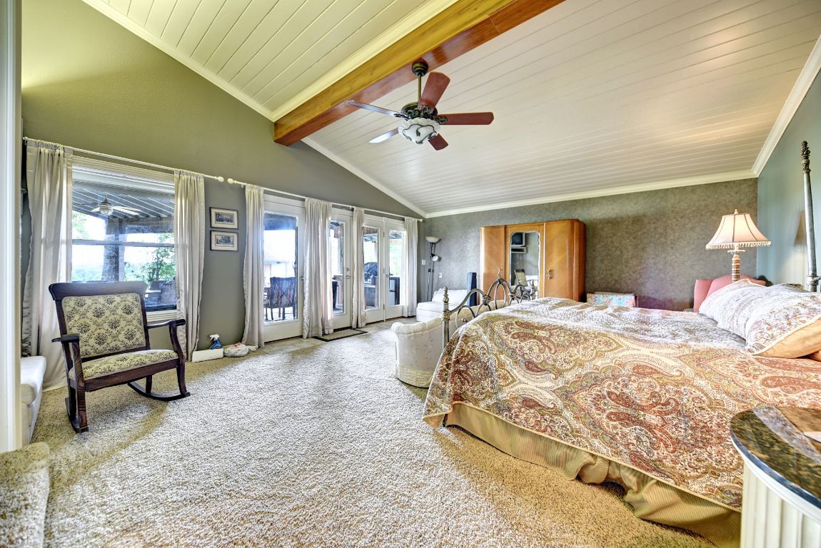 2575 Old Mill Creek Road Brenham, TX 77833 - Photo 21 of 40 a spacious bedroom with a large bed and a chandelier