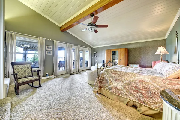 a spacious bedroom with a large bed and a chandelier