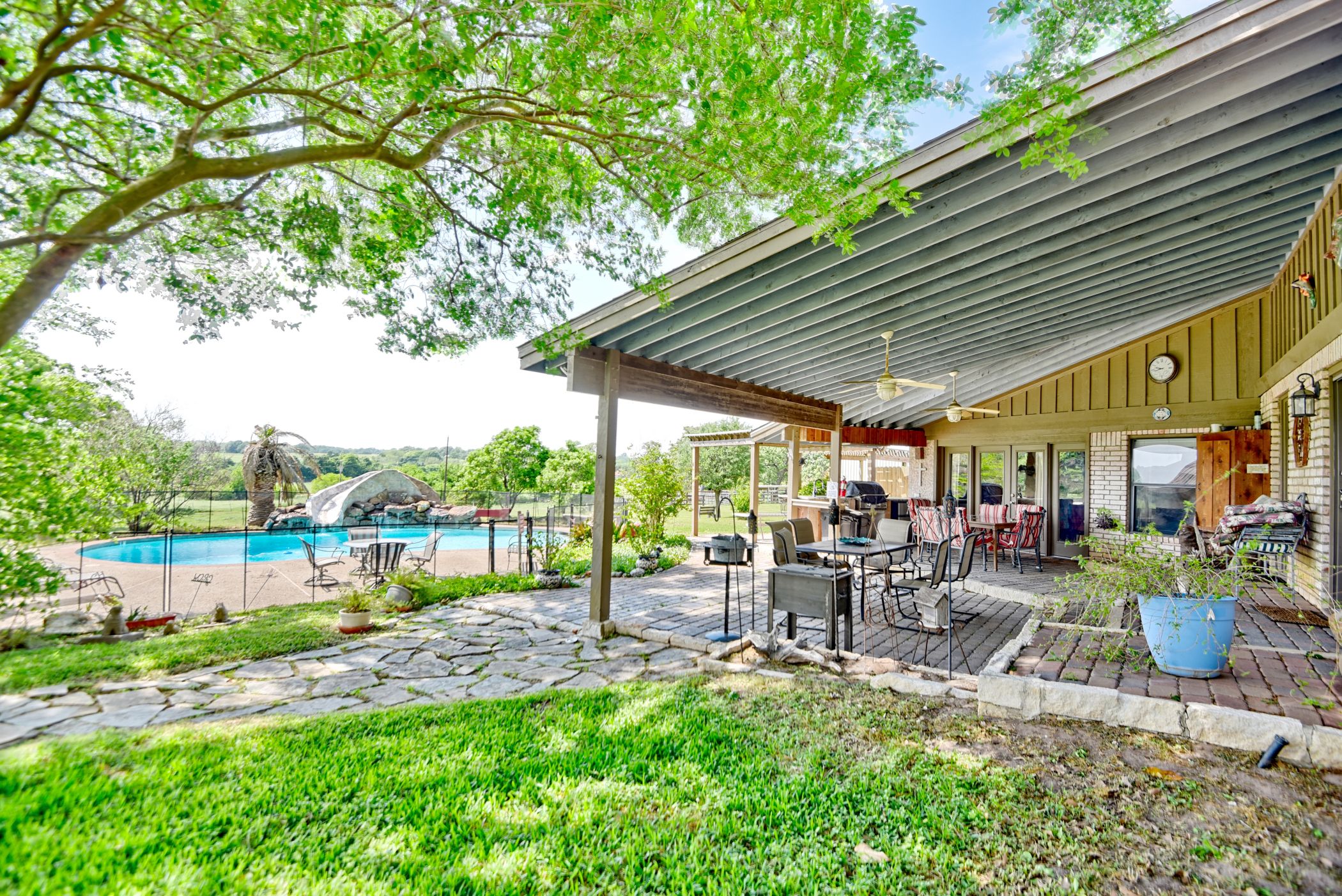2575 Old Mill Creek Road Brenham, TX 77833 - Photo 27 of 40 a view of a patio with table and chairs potted plants and large tree