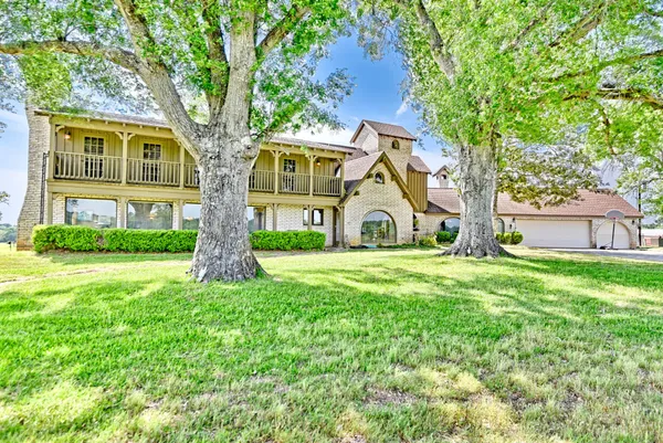 a view of house with a big yard and large trees