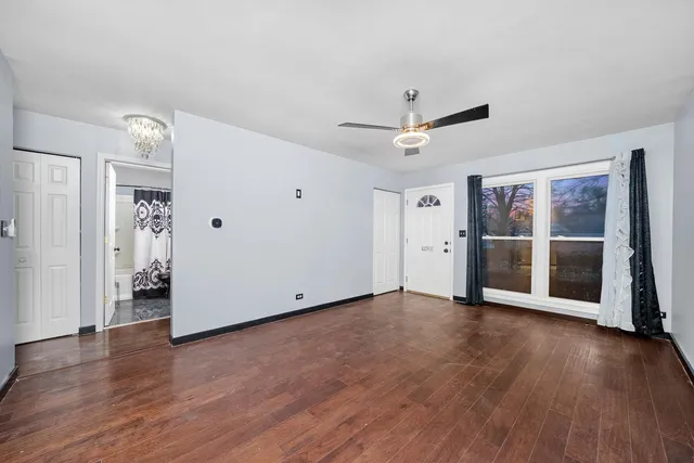 an empty room with wooden floor and ceiling fan