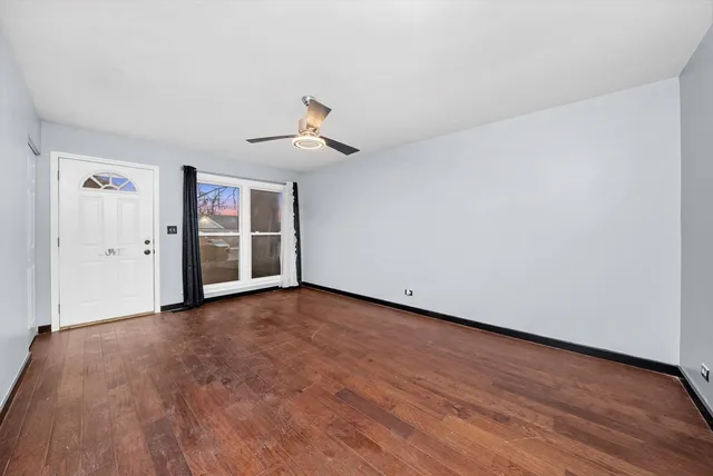 a view of empty room with wooden floor and ceiling fan