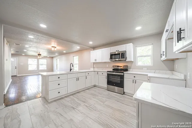 a large kitchen with granite countertop a large counter top space a sink stainless steel appliances and cabinets
