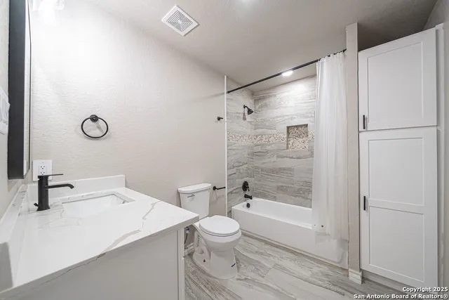 a bathroom with a shower sink vanity and toilet