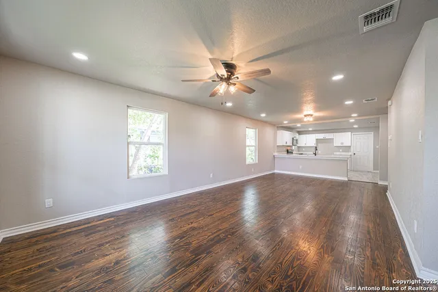 a view of an empty room with a window and wooden floor