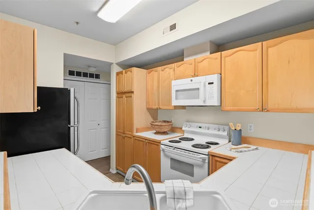 a kitchen with stainless steel appliances a stove a sink a refrigerator and a cabinets