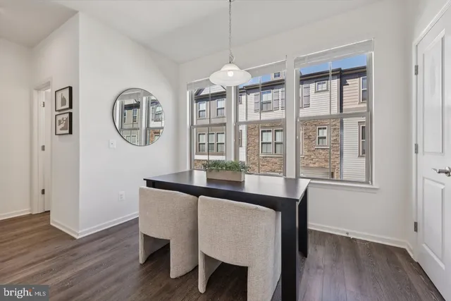 a dining room with wooden floor a glass table and windows