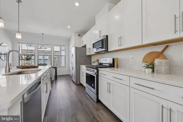 a large kitchen with stainless steel appliances granite countertop a lot of counter space and wooden floors